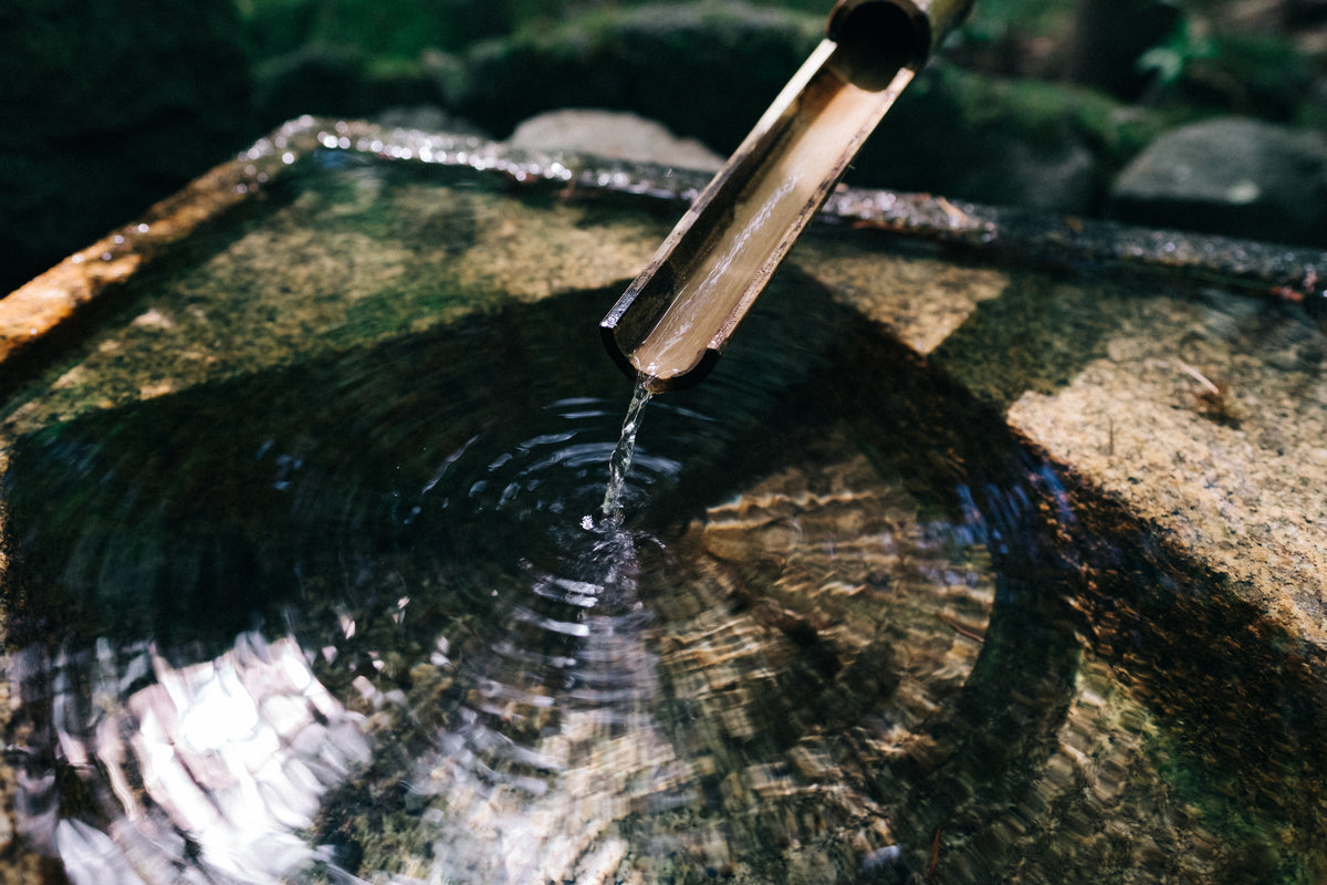 Bambus-Wasserspiel mit fließendem Wasser in einem natürlichen Steinbecken